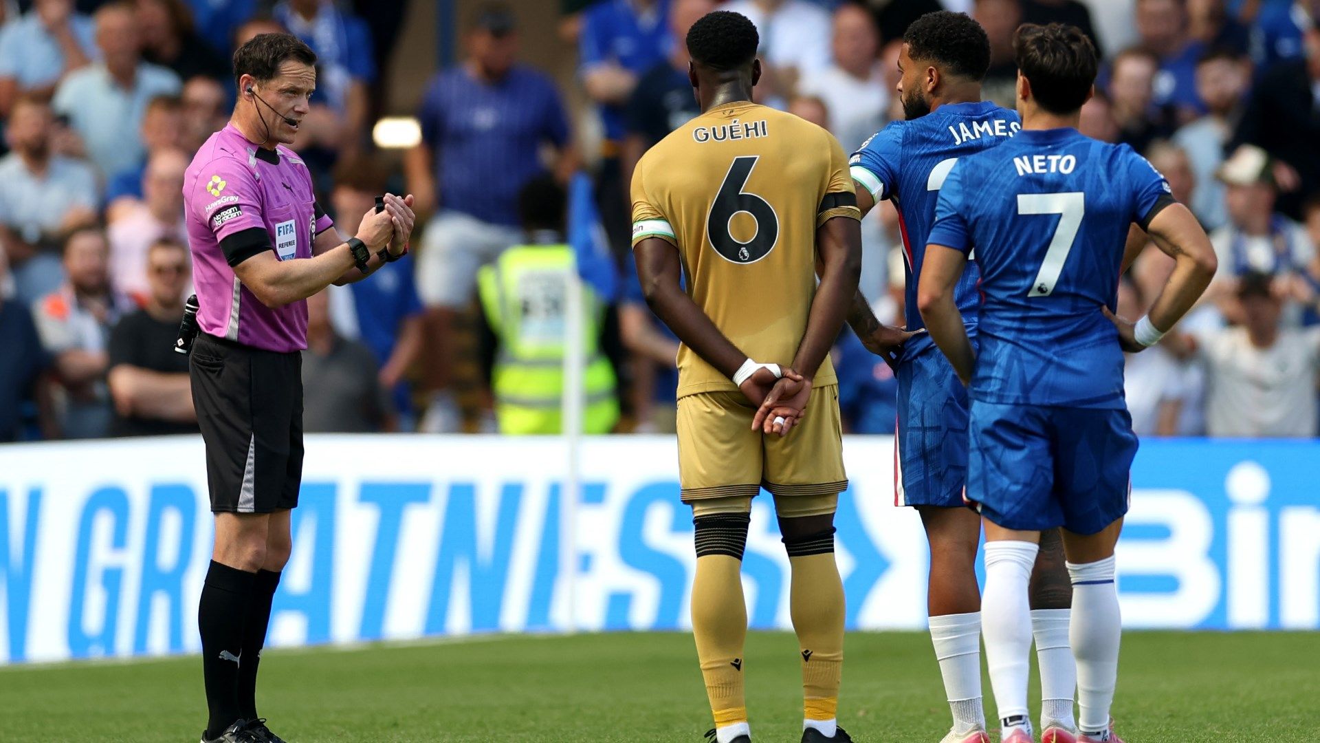 Referee Darren England speaks to Crystal Palace captain Marc Guehi and Chelsea captain Reece James