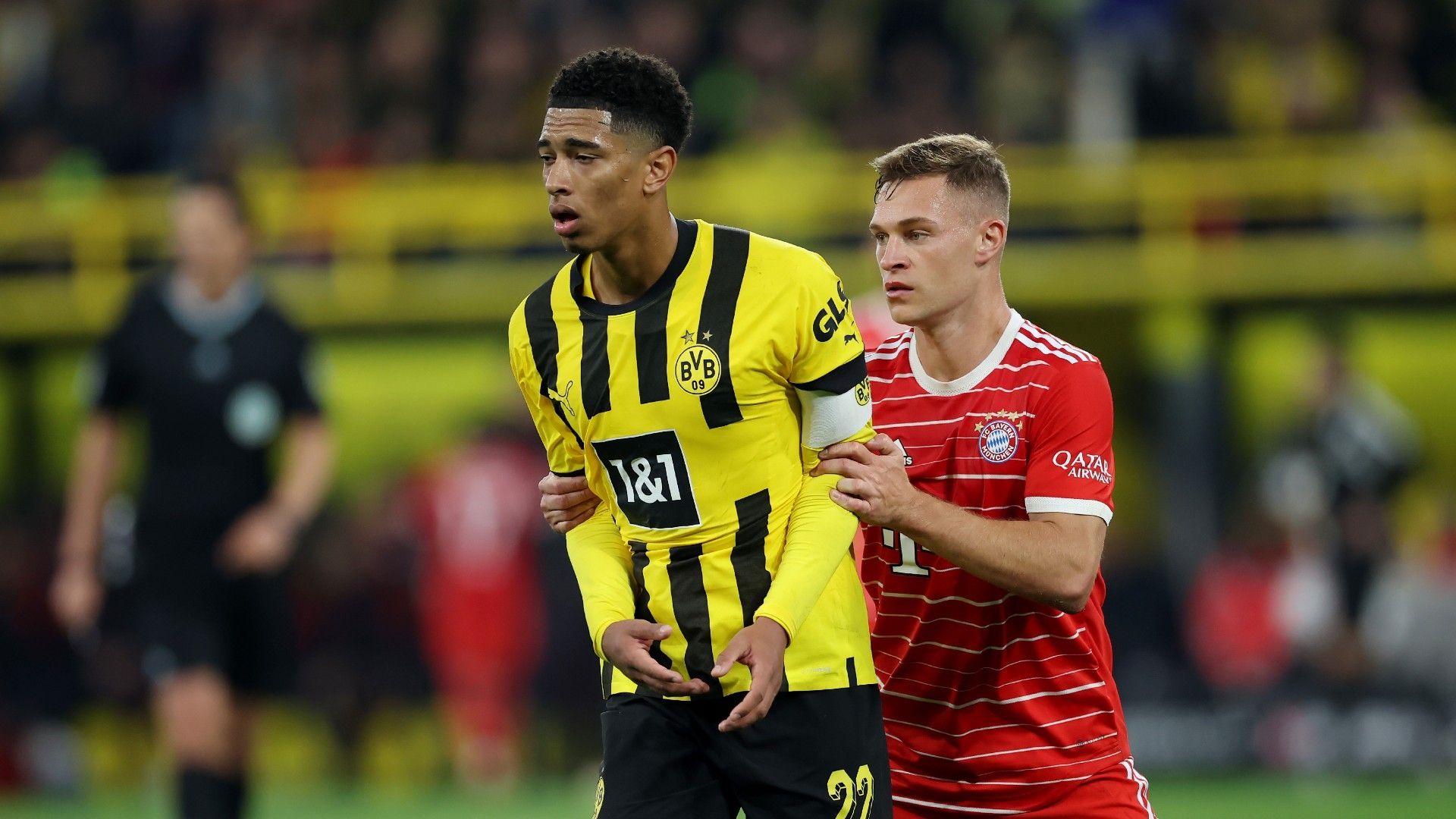Jude Bellingham of Borussia Dortmund is challenged by Joshua Kimmich of Bayern Munich
