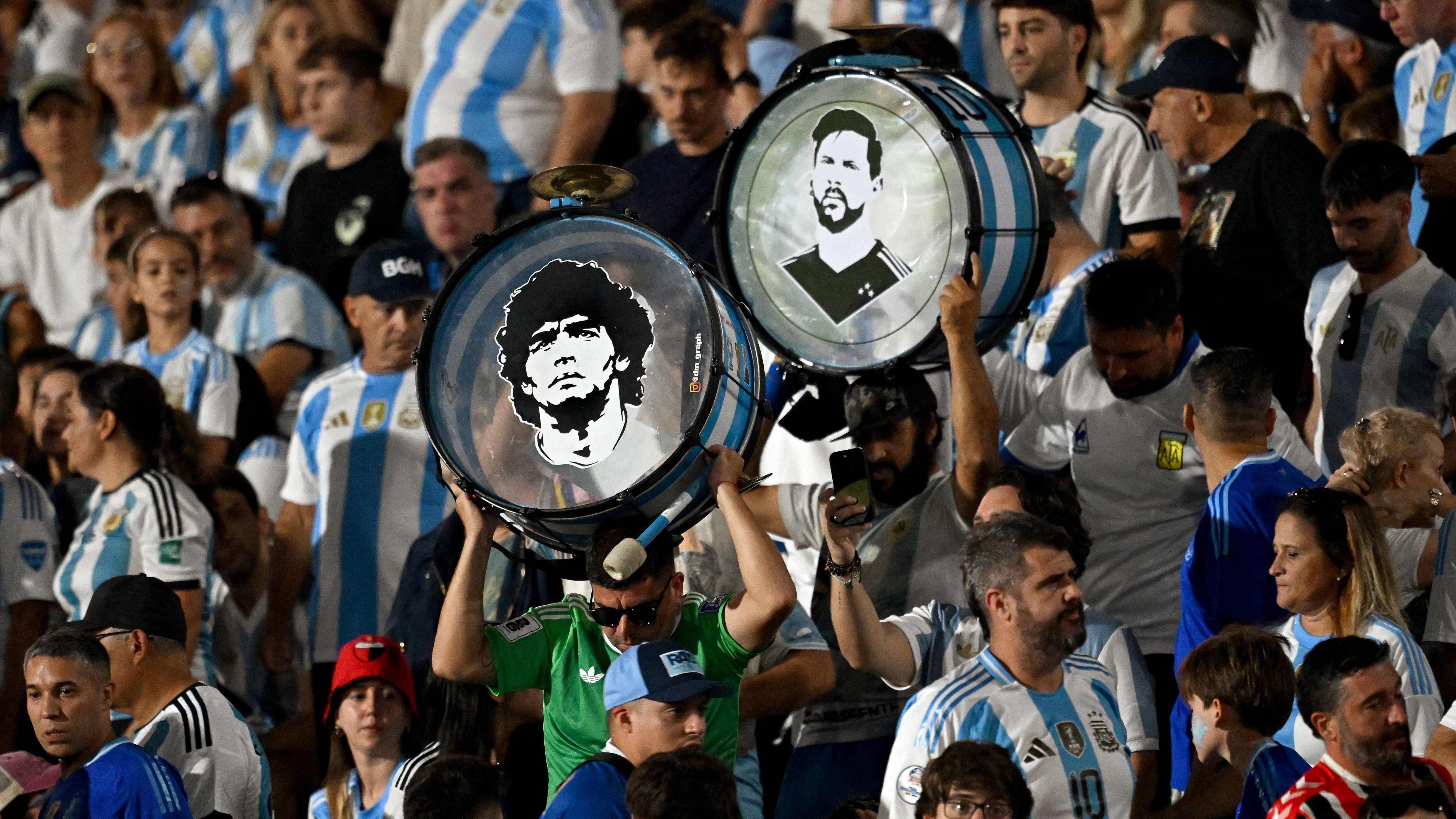 The faces of late Argentine football legend Diego Maradona (L) and Argentina's forward Lionel Messi are seen on the drums of Argentina's fans 