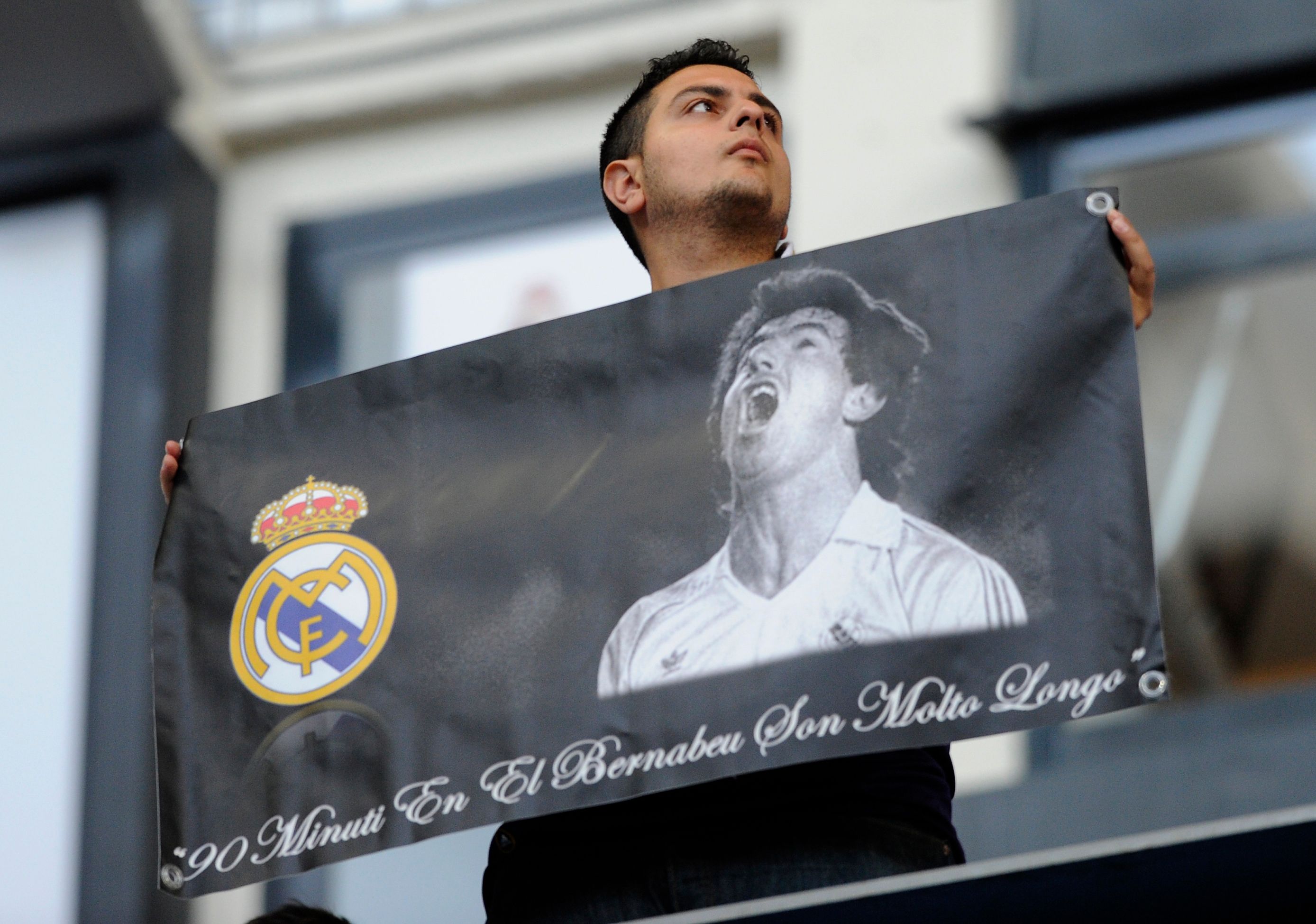 A supporter of Real Madrid holds a banner depicting late Real Madrid's forward Juan Gomez Gonzalez  Juanito