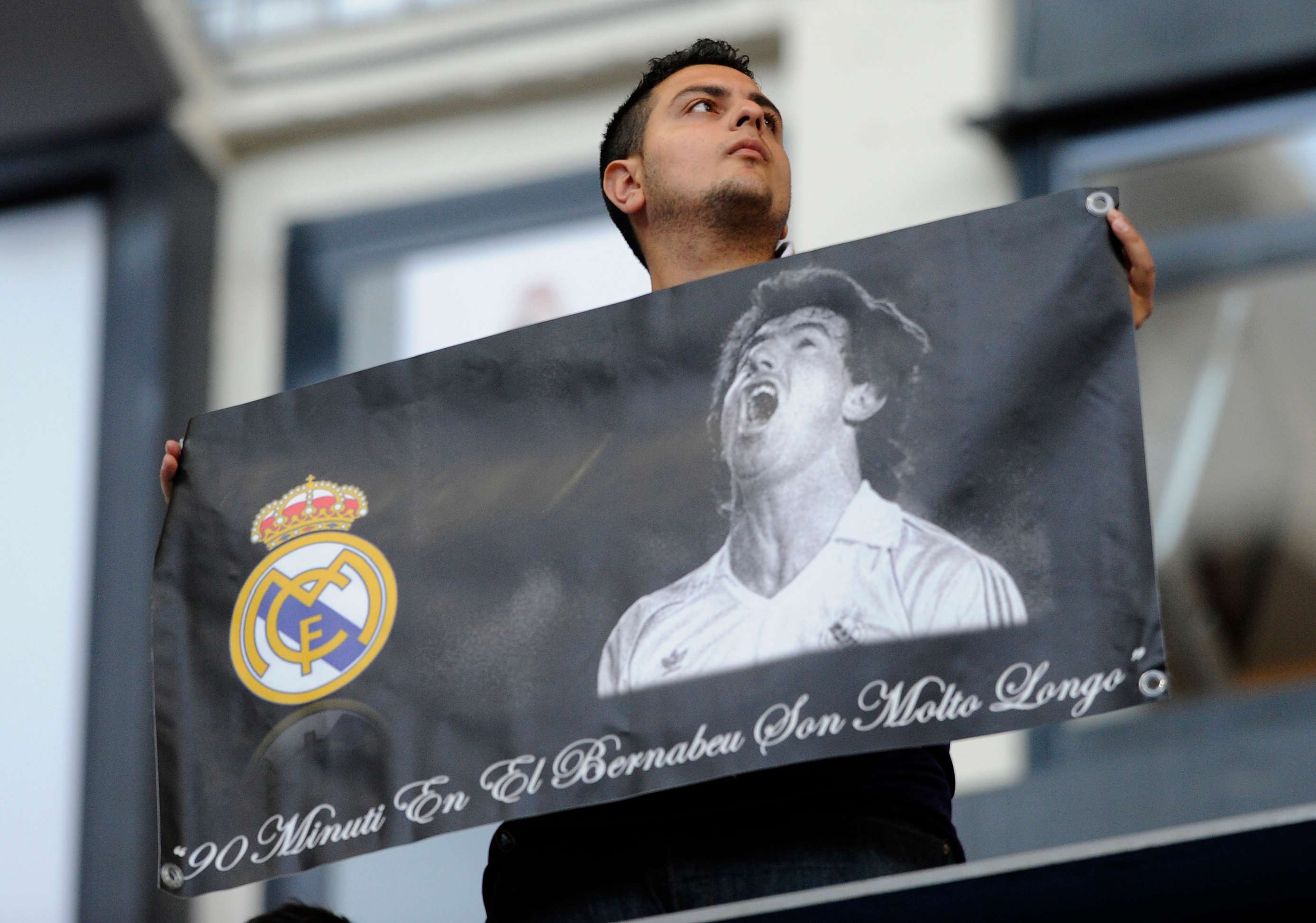 A supporter of Real Madrid holds a banner depicting late Real Madrid's forward Juan Gomez Gonzalez  Juanito
