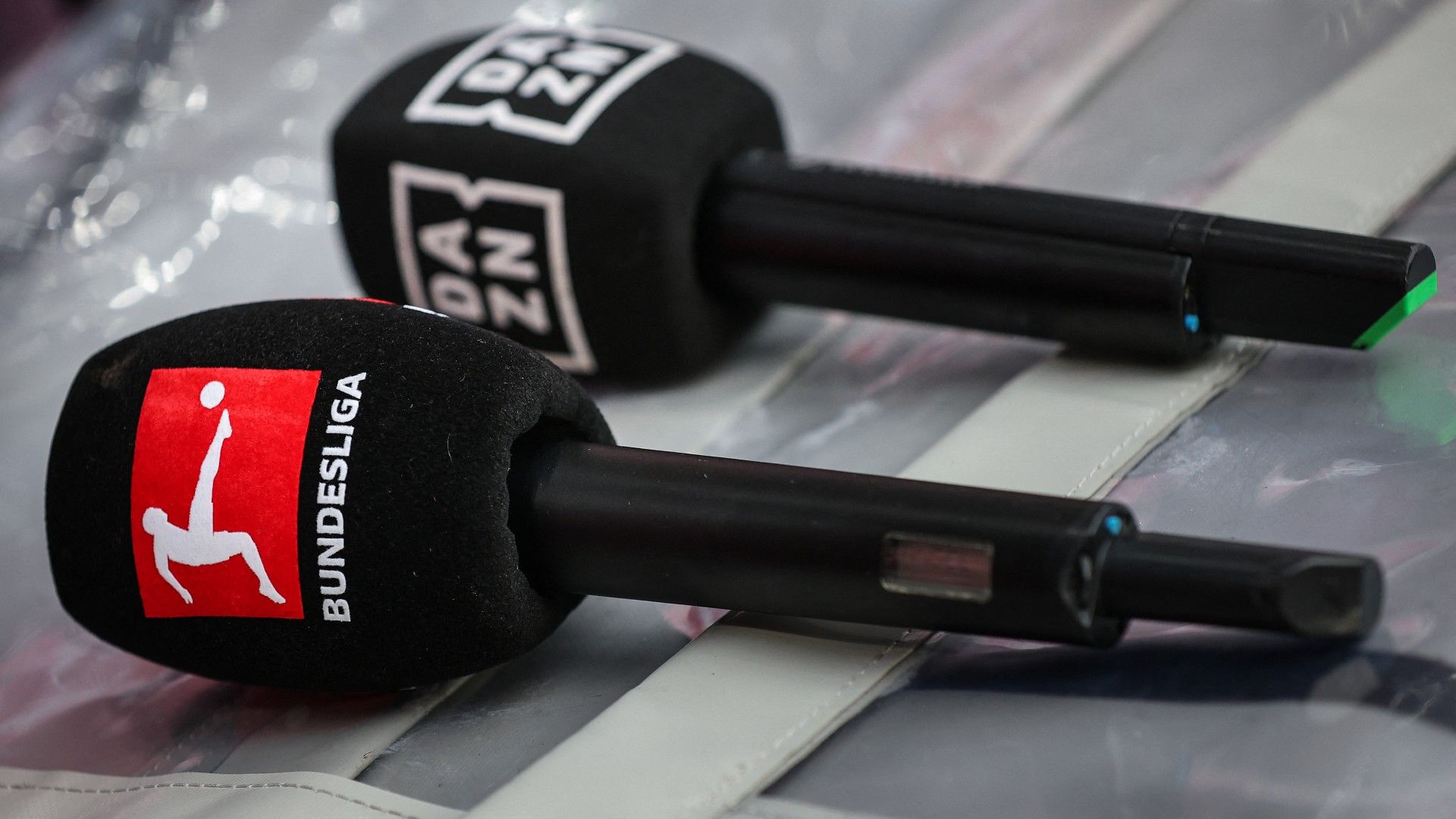 Microphones with the logos of to the British sports streaming and entertainment platform's DAZN (R) and German division Bundesliga