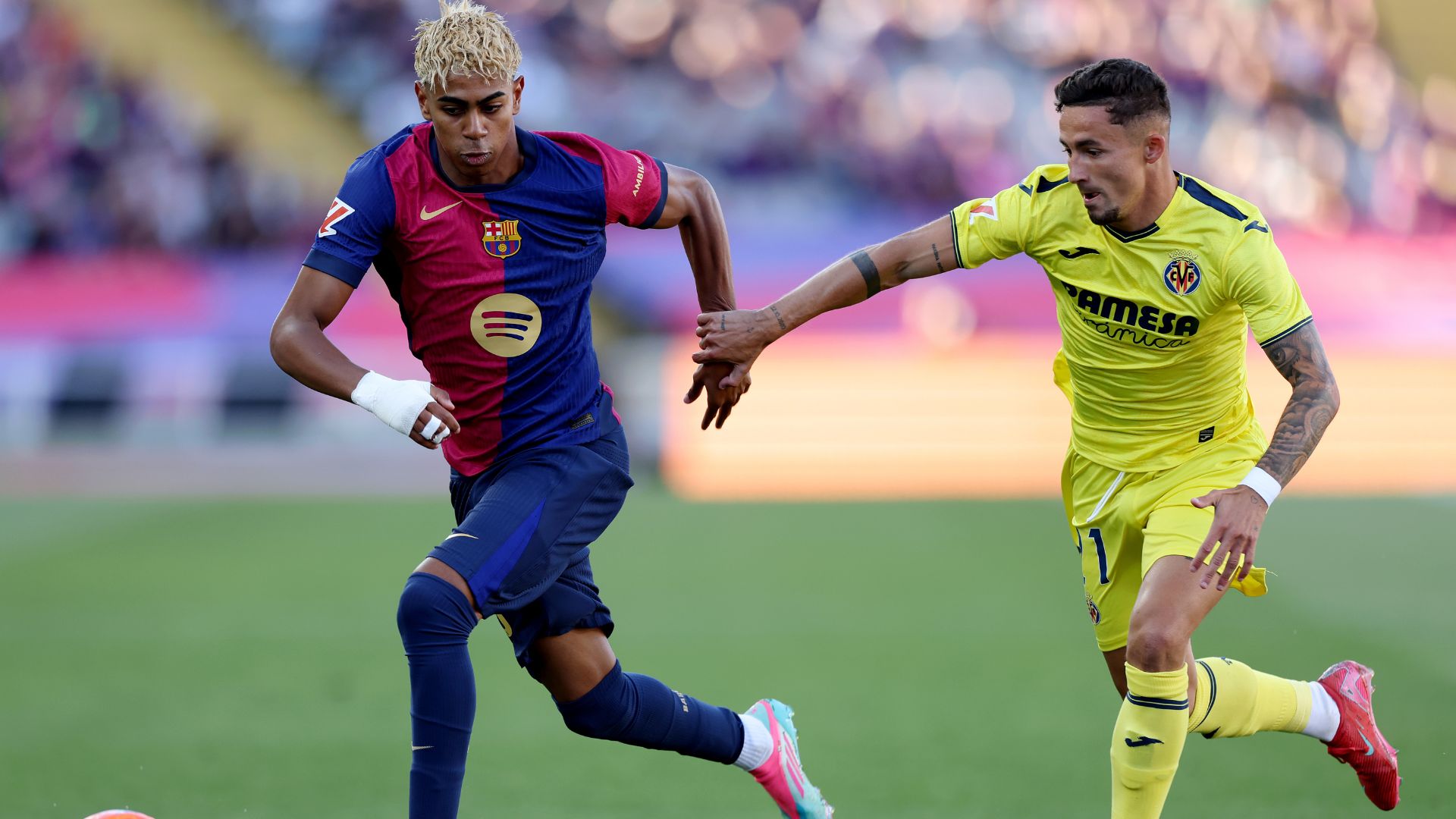 Lamine Yamal of FC Barcelona runs with the ball whilst under pressure from Yeremy Pino of Villarreal CF