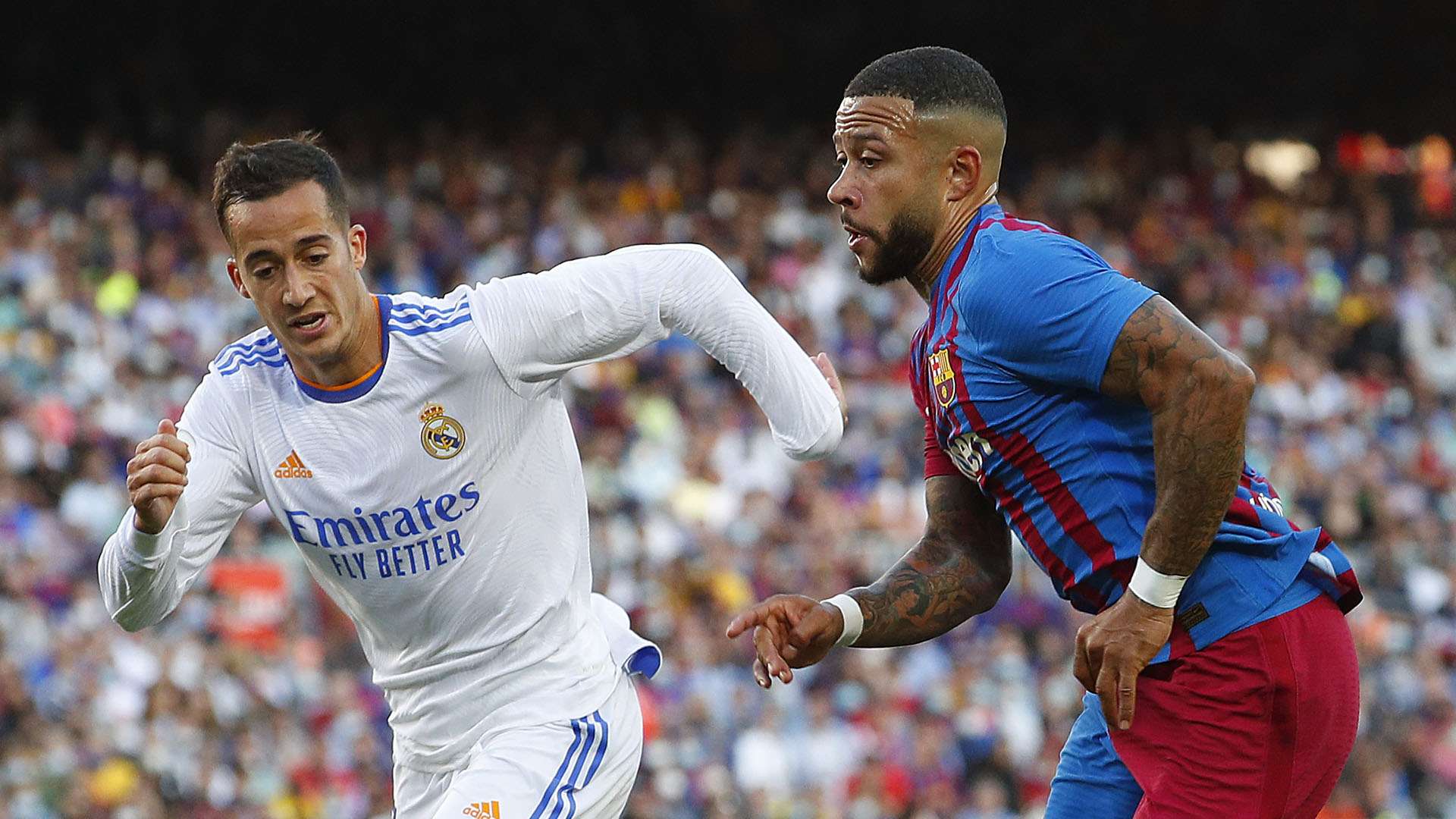 Memphis Depay of FC Barcelona runs with the ball whilst under pressure from Lucas Vazquez of Real Madrid