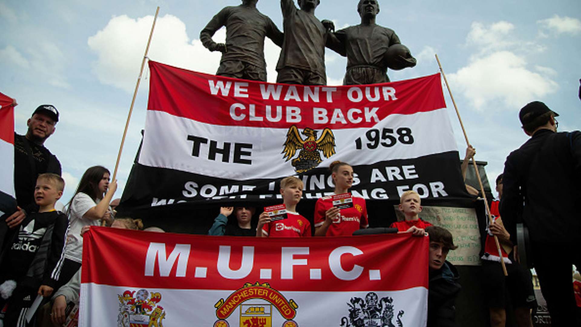 Protesters stand in front of the statue stationed outside...