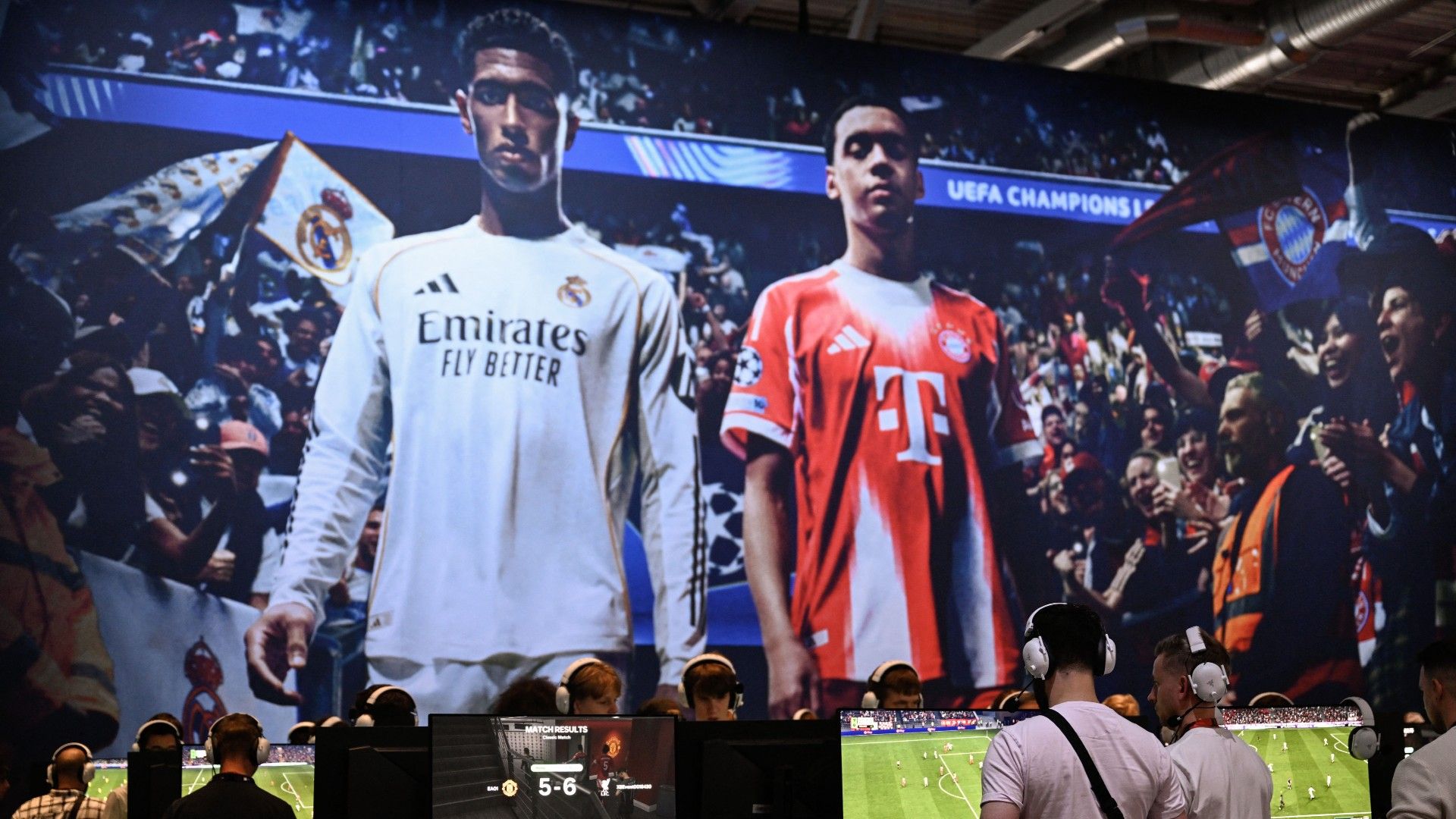  Gamers play the video game EA Sports FC 26 in front of a screen featuring English midfielder Jude Bellingham (L) and Bayern Munich's German midfielder Jamal Musiala