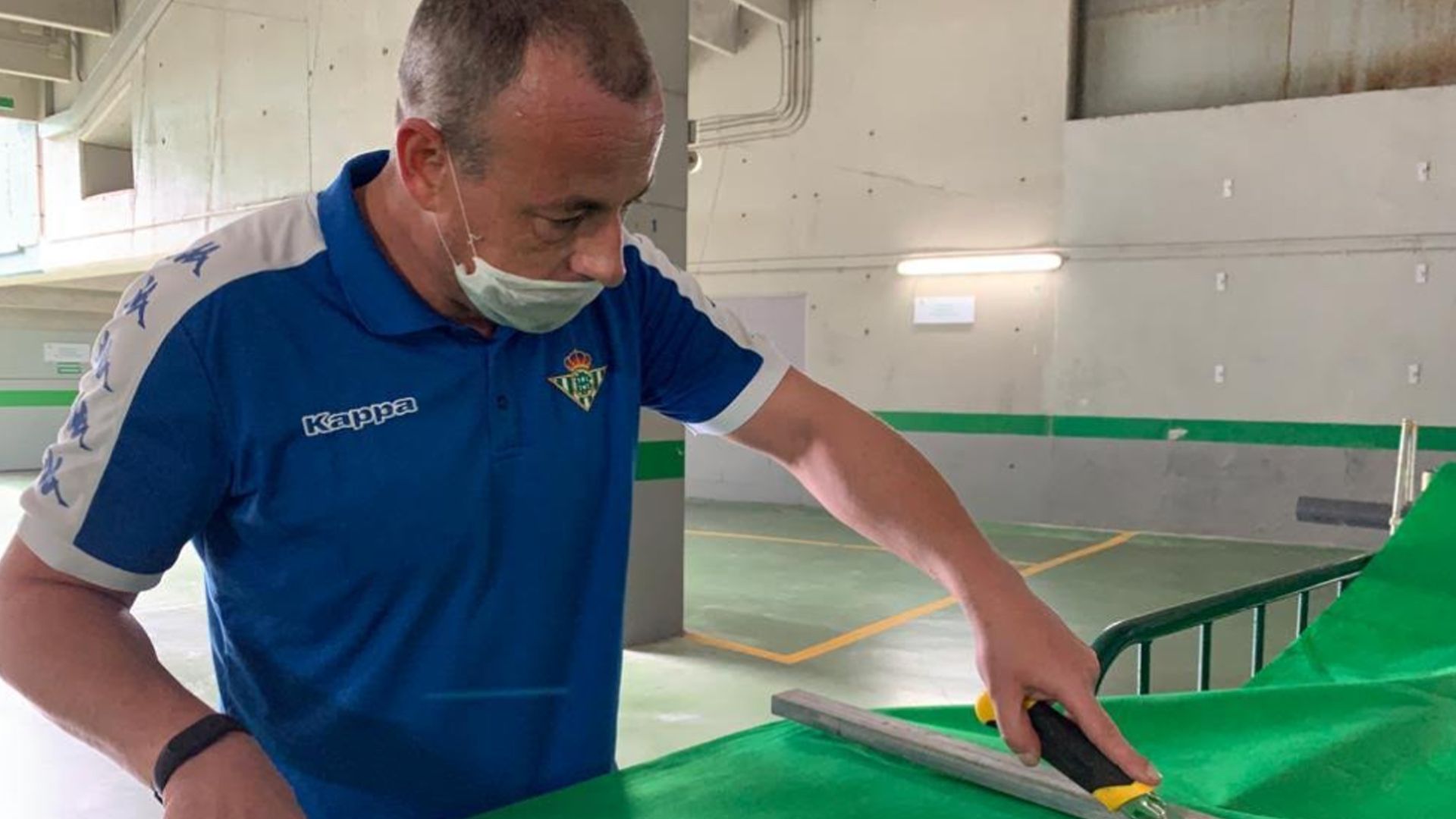 Un miembro del Betis haciendo una bata sanitaria