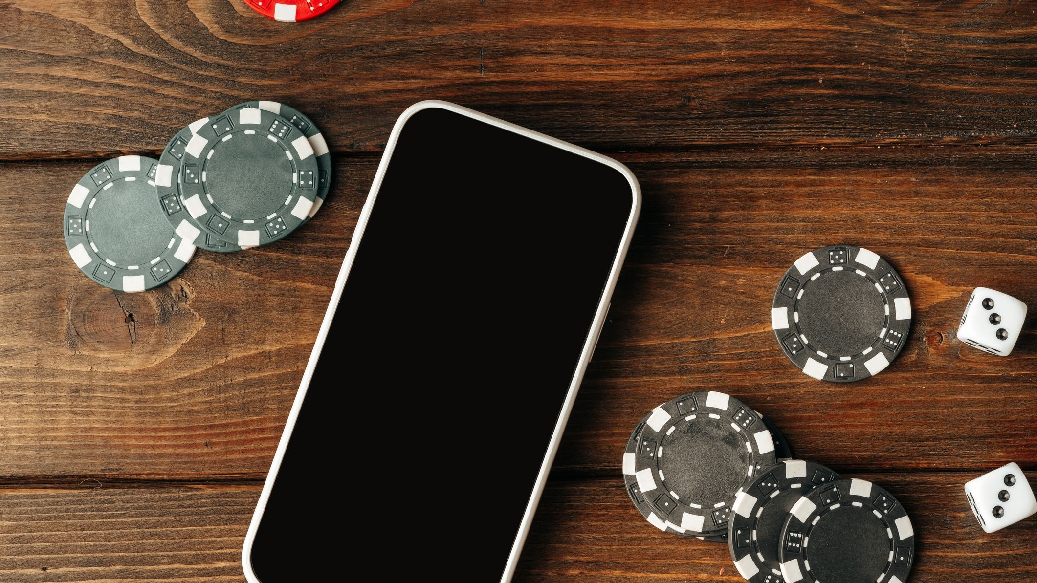 Poker chips and smartphone on wooden table close up. 