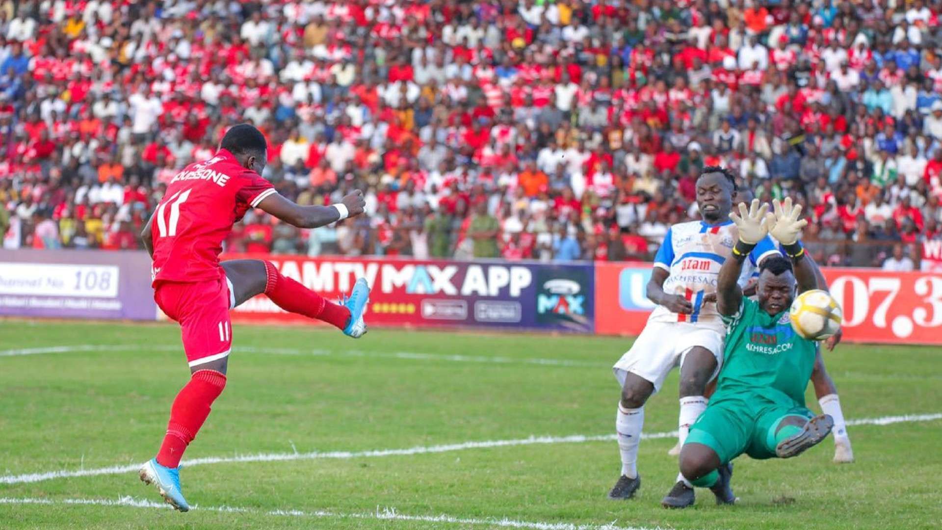 Simba SC player Luis Miquissone scores past Mathews Kigonya of Azam FC.