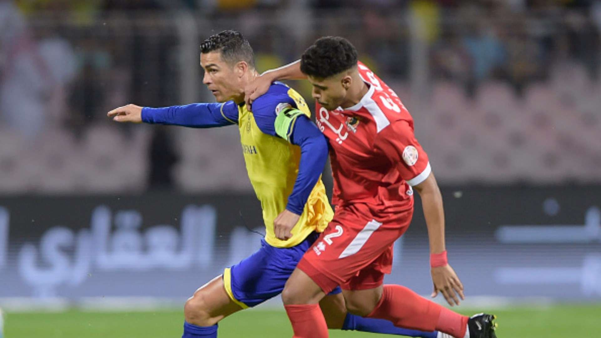 Cristiano Ronaldo of Al Nassr tussles with Ali Abdulqader Makki of Al-Wehda