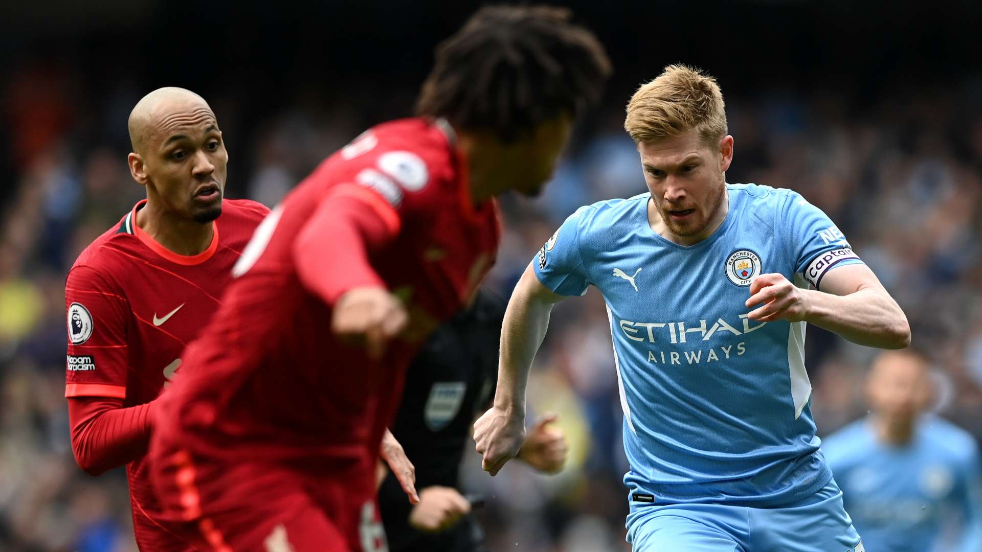 Де Брюйне между символами Манчестер Сити и Ливерпуля