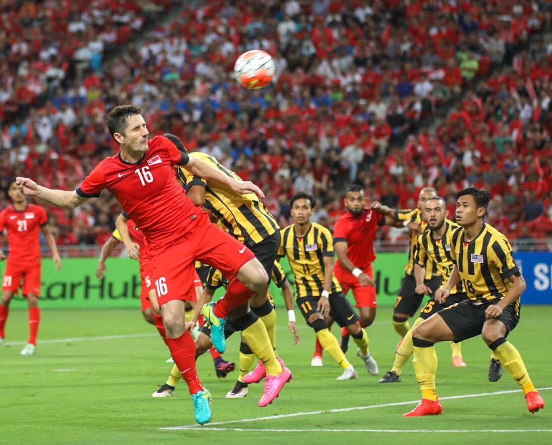 Singapore's Daniel Bennett winning a header againt Malaysia's Shahrul Saad