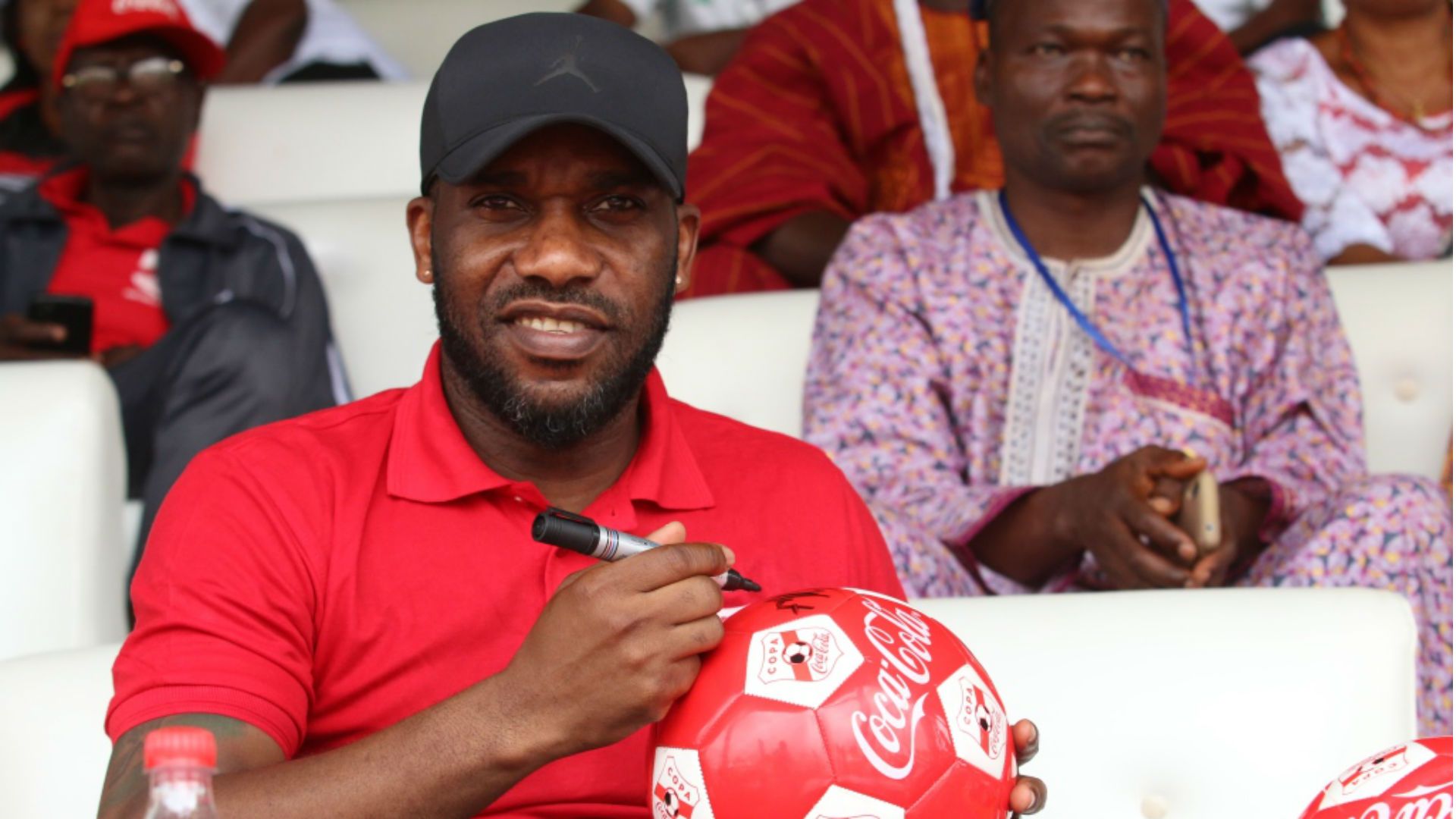Jay Jay Okocha autographs footballs for fans