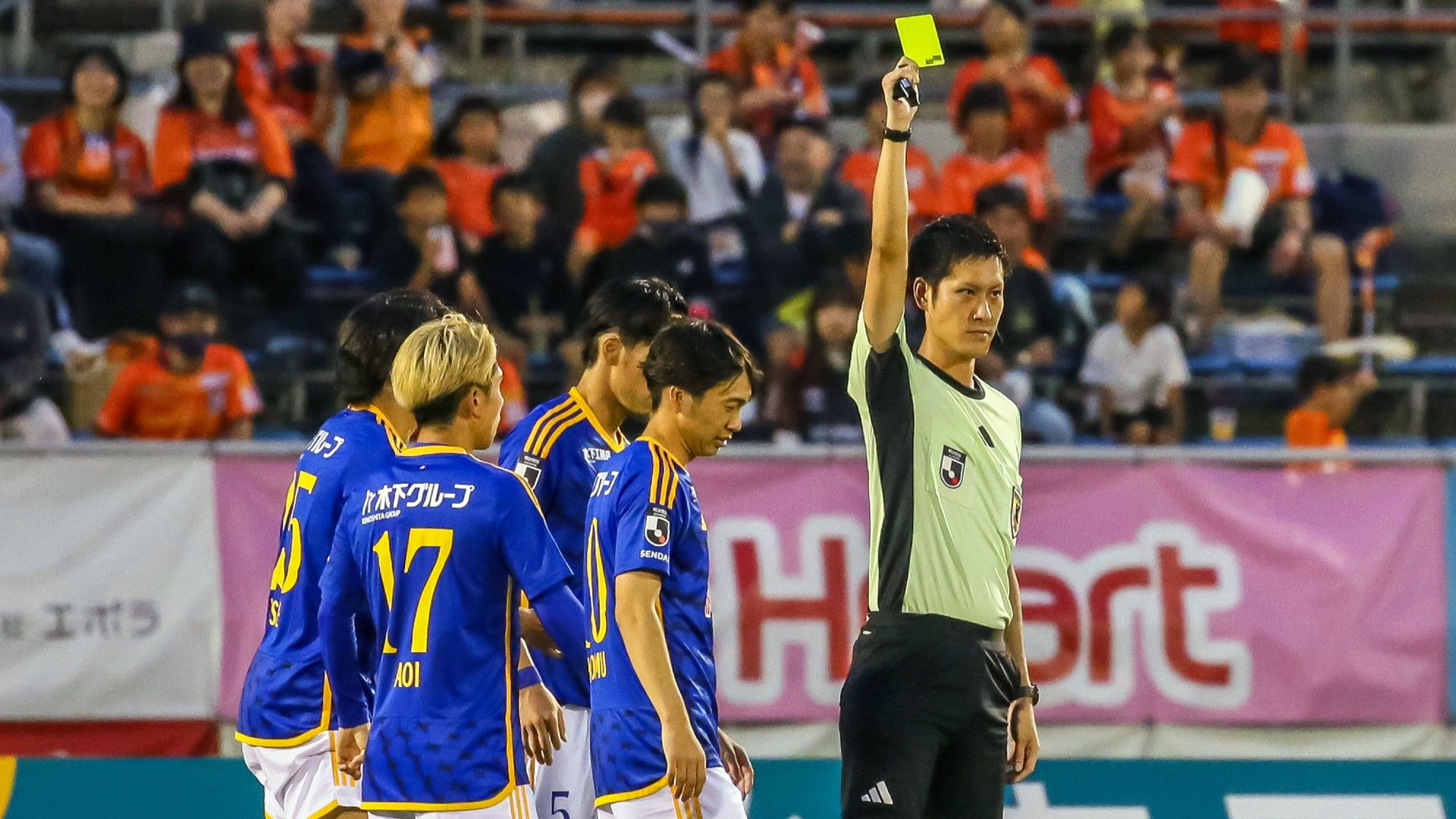 Referee Yusuke Ohashi shows a yellow card 