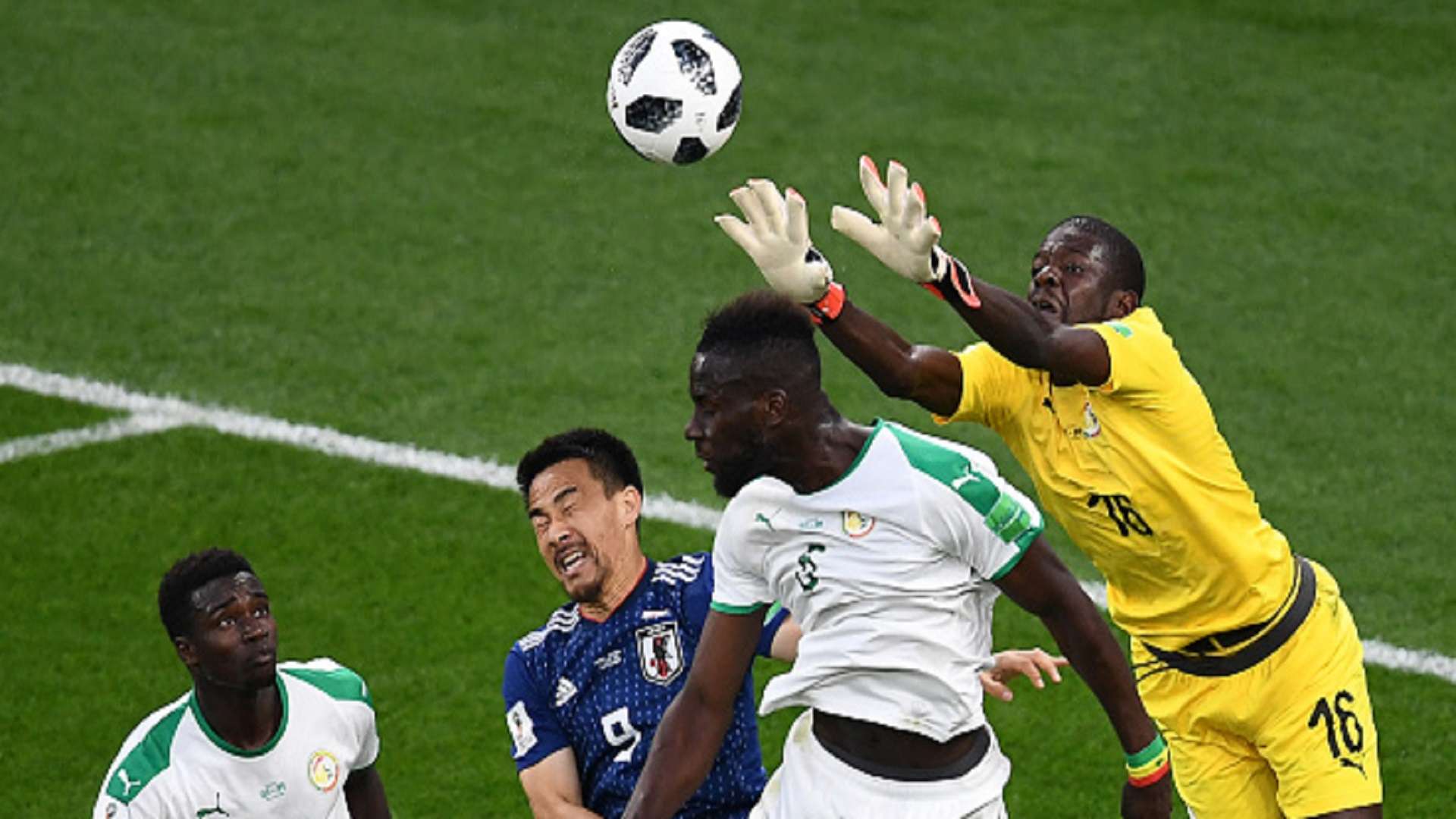 Khadim N'Diaye jumps to clear a ball beside Senegal's defender Moussa Wague, Japan's forward Shinji Okazaki
