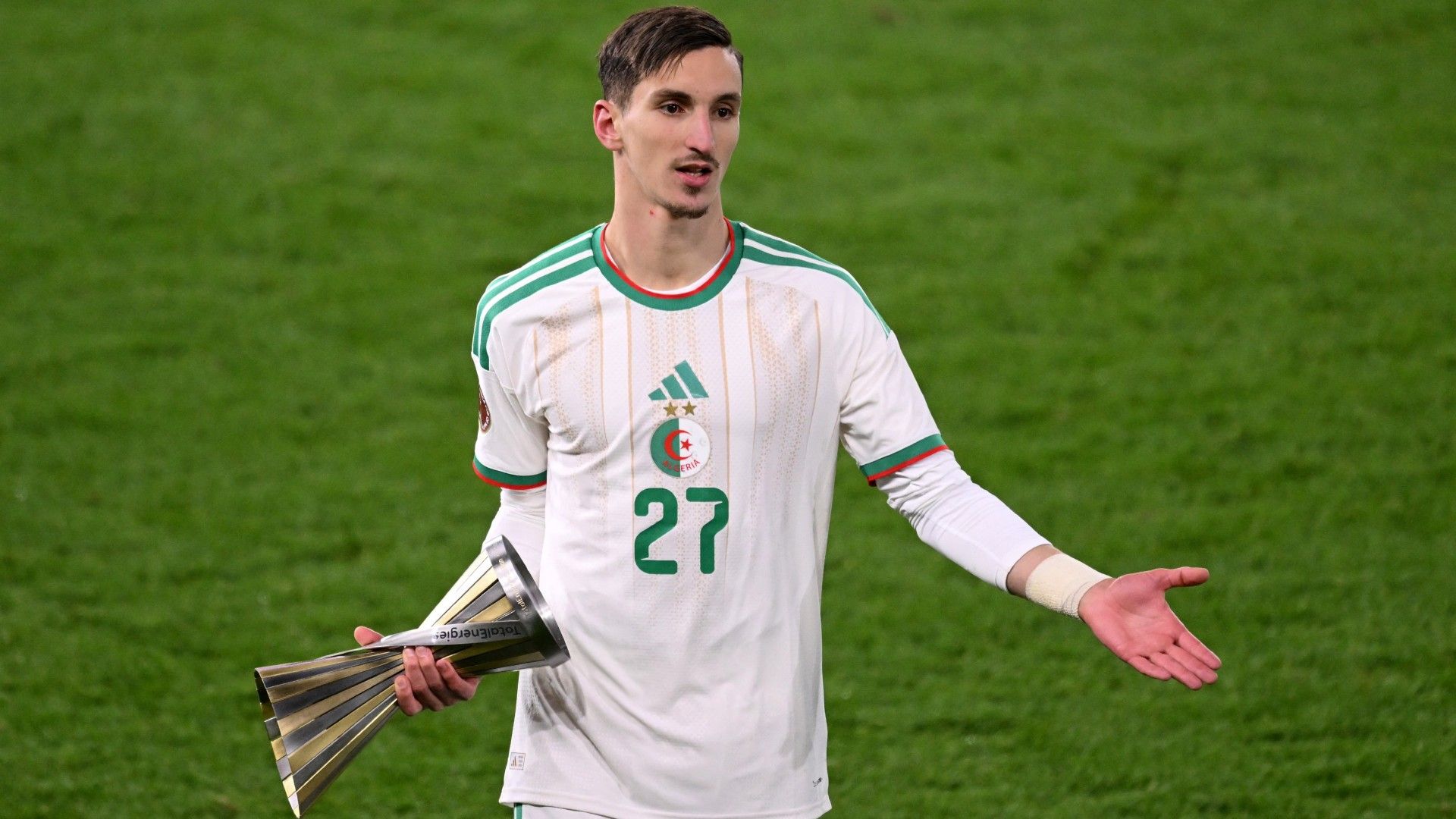 Algeria's forward #27 Adil Boulbina celebrates with the player of the match trophy