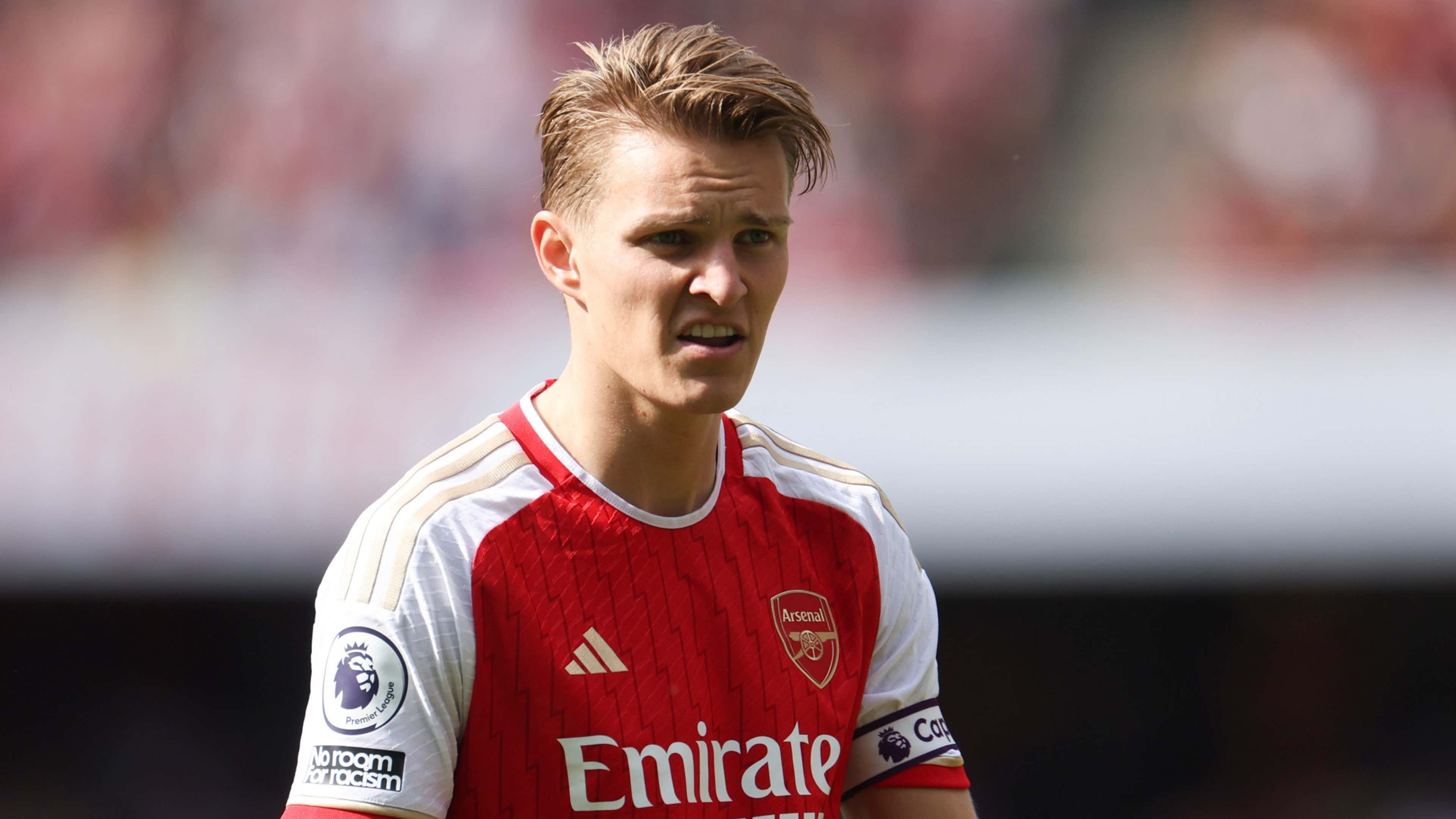  Martin Odegaard, a Norwegian professional footballer who plays as a midfielder for Premier League club Arsenal, is seen here in his team's kit with a pensive expression on his face during a match.