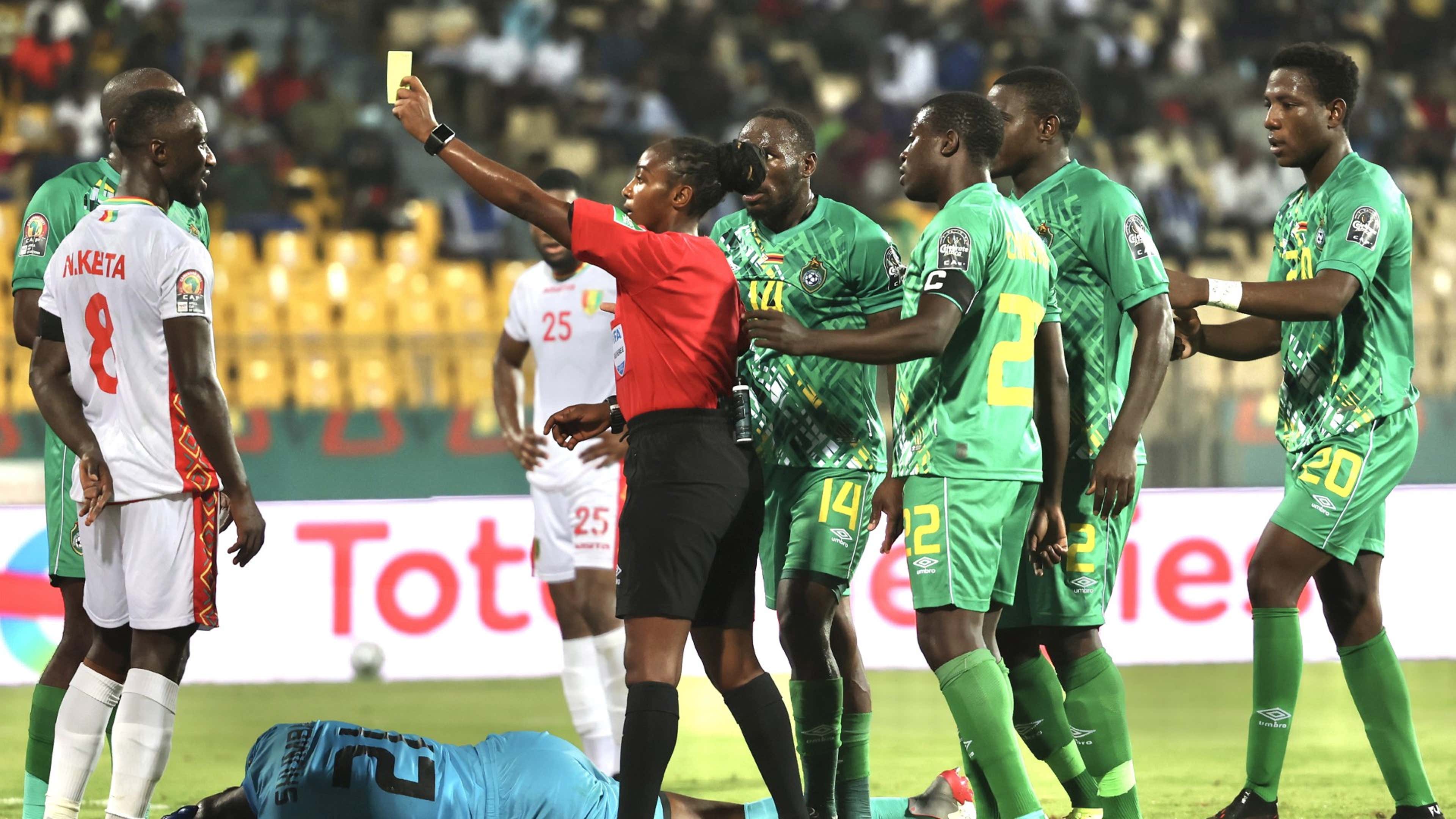 Referee Salima Rhadia Mukansanga of Rwanda shows a yellow card to Guinea captain Naby Keita.