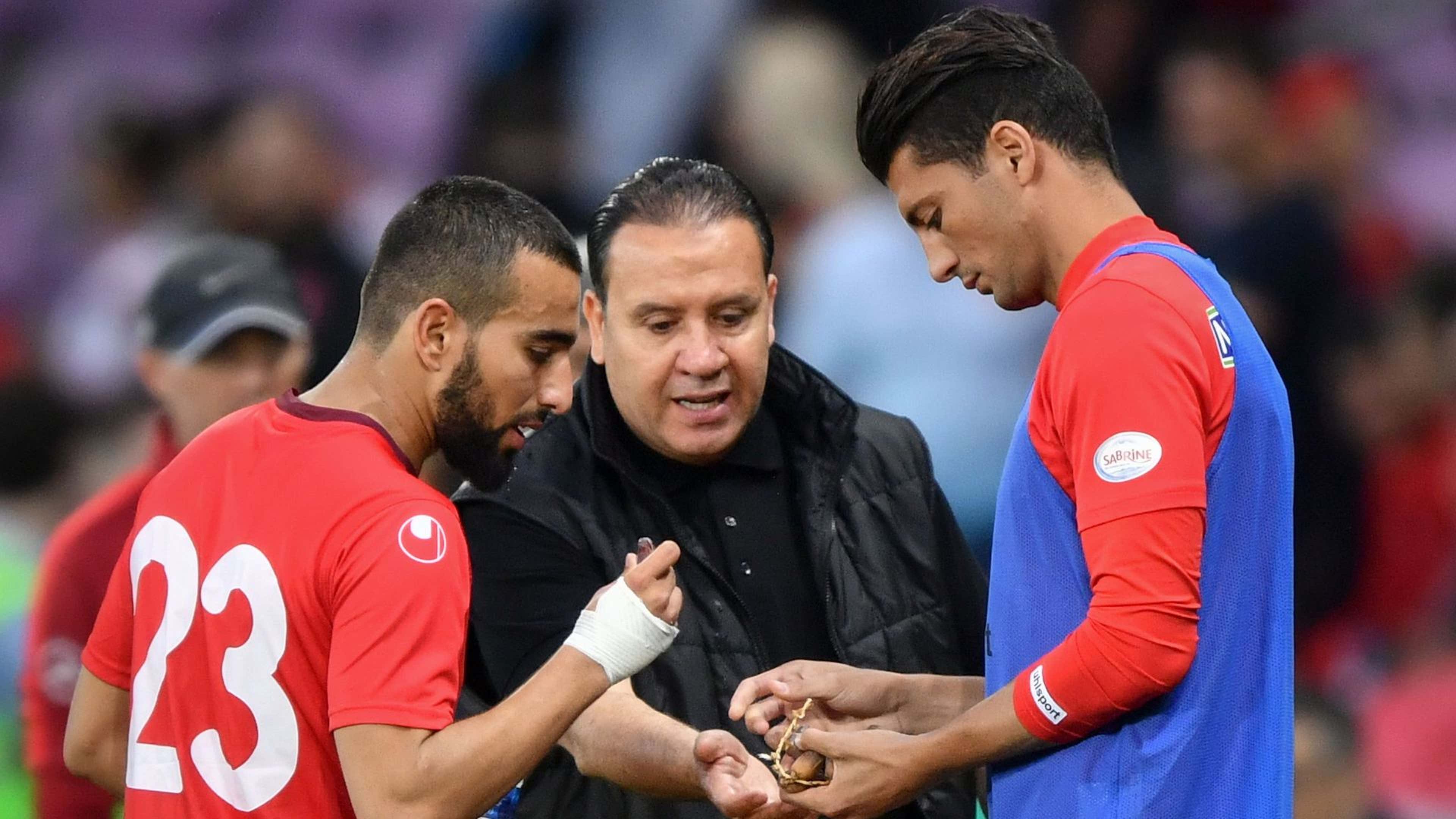Tunisia's head coach Nabil Maaloul (C) distributes dates to Tunisia's midfielder Naim Sliti (L) and Tunisia's defender Rami Bedoui